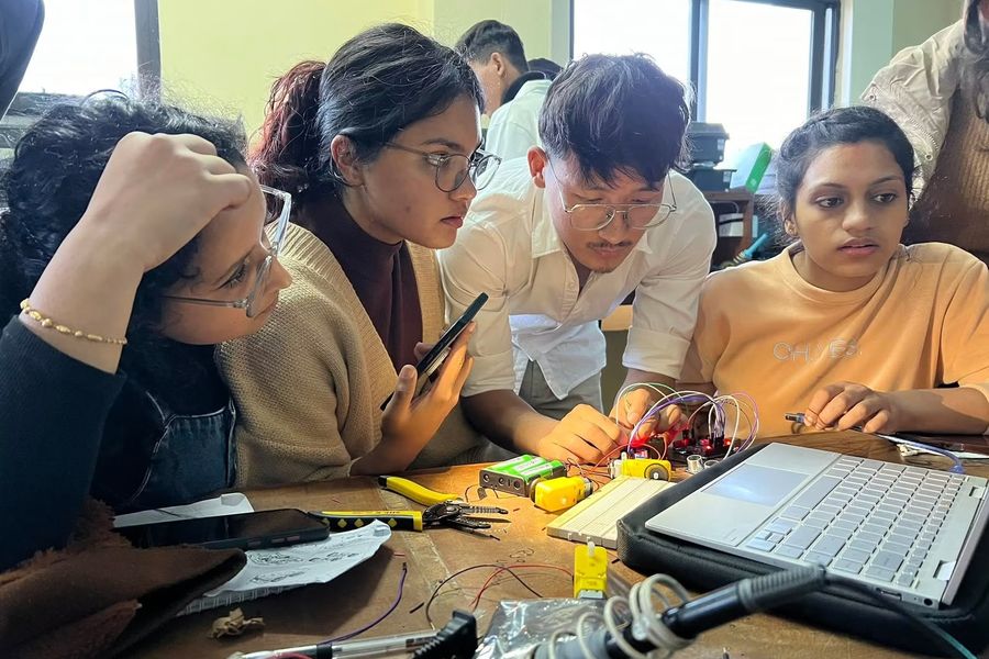 Aashish Rai helping students debug a breadboard circuit during a robotics session